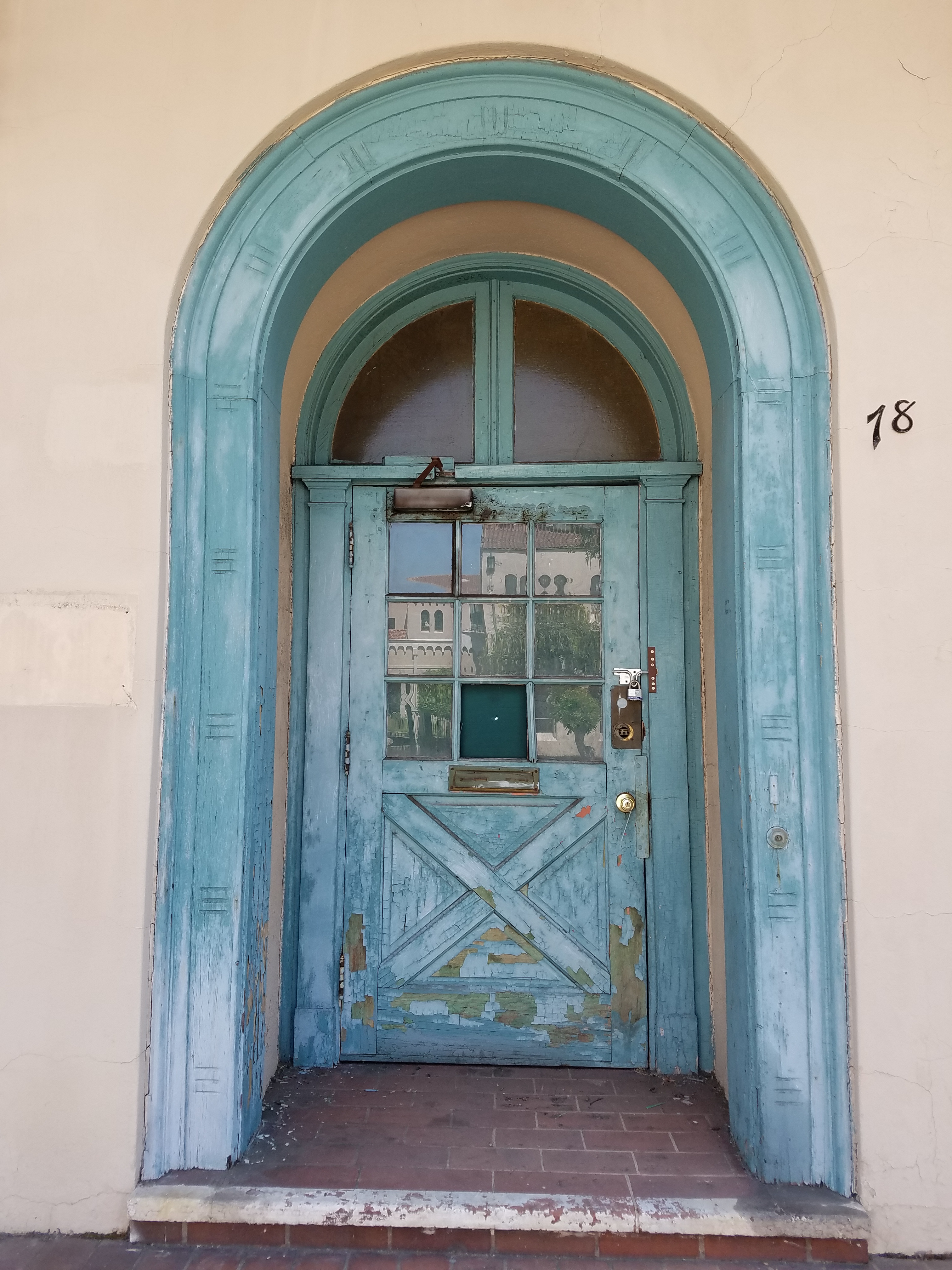 Light aqua arch surrounding an inset wooden door of the same color